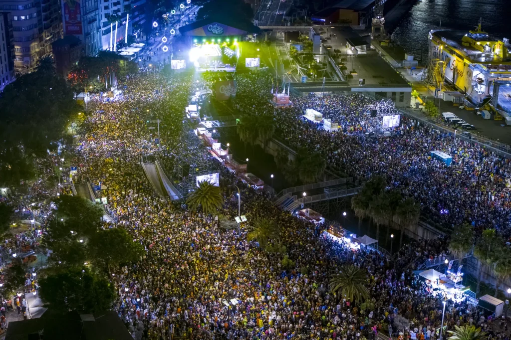 Fiesta callejera del Carnaval de Tenerife 2026 con trajes coloridos y multitudes bailando en la Plaza de España de Santa Cruz