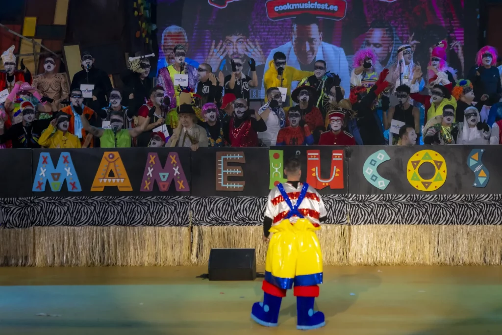 Grupo de murga actuando en el Carnaval de Tenerife 2026 con silbatos de kazoo y disfraces satíricos en el Recinto Ferial.
